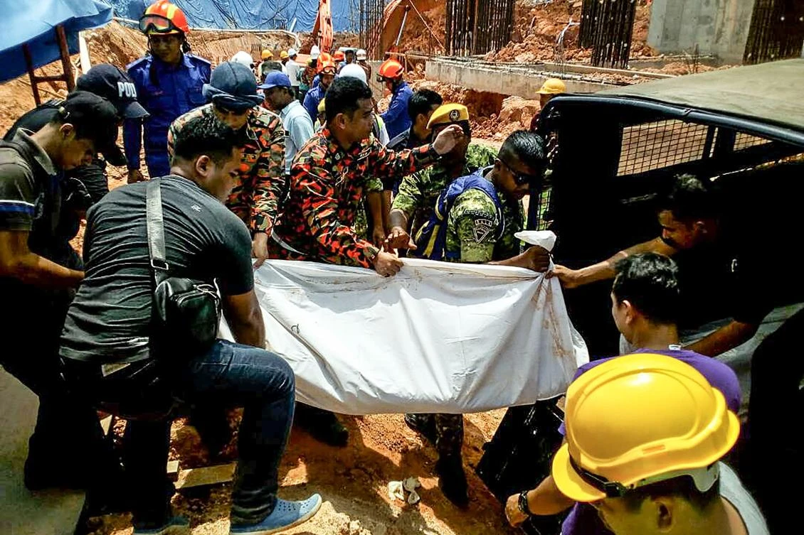 Above, rescue workers carry a landslide victim into a lorry at a construction site in Tanjung Bungah aorth of Penang. (Fire and Rescue Department of Malaysia / AFP)