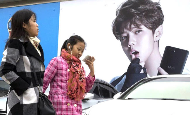 Chinese women walk past advertisement featuring teen idol Lu Han, also known as China’s Justin Bieber in Beijing, China. (AP)