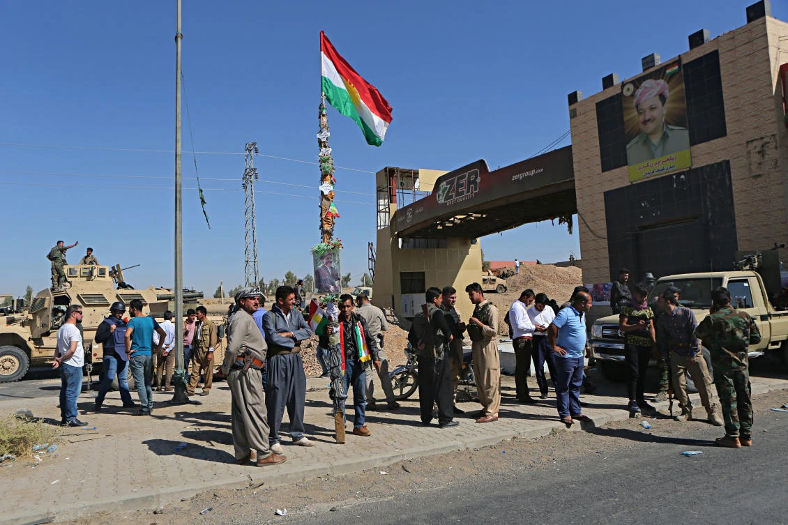 A picture of Massoud Barzani, the President of Iraq’s autonomous Kurdish region, and a Kurdish flag are displayed as Kurdish security forces stand guard in Altun Kupri, on the outskirts of Irbil, Iraq, on Thursday, October 19, 2017. (File photo by AP)