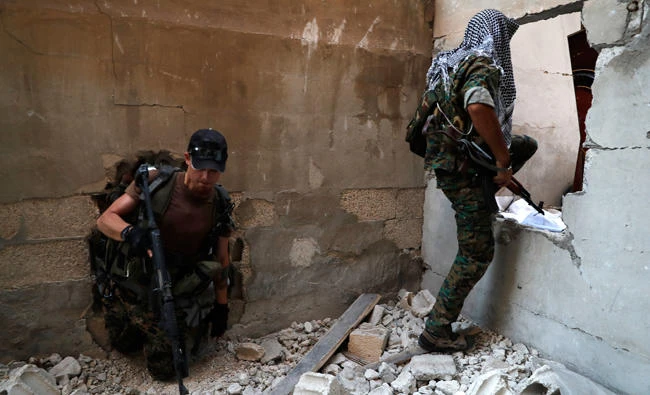 U.S.-backed Syrian Democratic Forces fighters, pass through holes as they cross from building to building to hide from snipers, on the front line with Daesh group militants in Raqqa, Syria. (AP)
