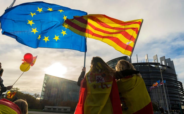 Women hold a Catalan and a European flag during a demonstration against Catalonia's independence in front of the European Parliament building in Strasbourg, France, on October 24, 2017. (AFP / PATRICK HERTZOG)
