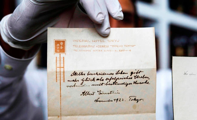 A photo taken on October 19, 2017, shows Gal Winner, owner and manager of the Winner's auction house in Jerusalem, displays one of two notes written by Albert Einstein, in 1922, on hotel stationary from the Imperial Hotel in Tokyo Japan. (AFP)