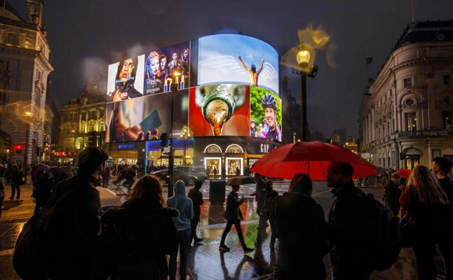 Pedestrians walk past the Piccadilly Circus advertisement screens in London on October 26, 2017. Retail sales in the UK dropped in October at the fastest pace since 2009, a CBI survey showed. (AFP / Tolga Akmen)