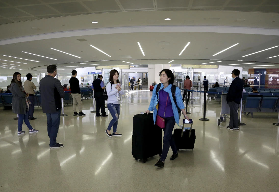 A traveler walks with her luggage after exiting the customs and immigration area at Newark Liberty International Airport in New Jersey. Long-haul carriers are starting new screening procedures for US-bound passengers after receiving new security guidelines from authorities. (AP)
