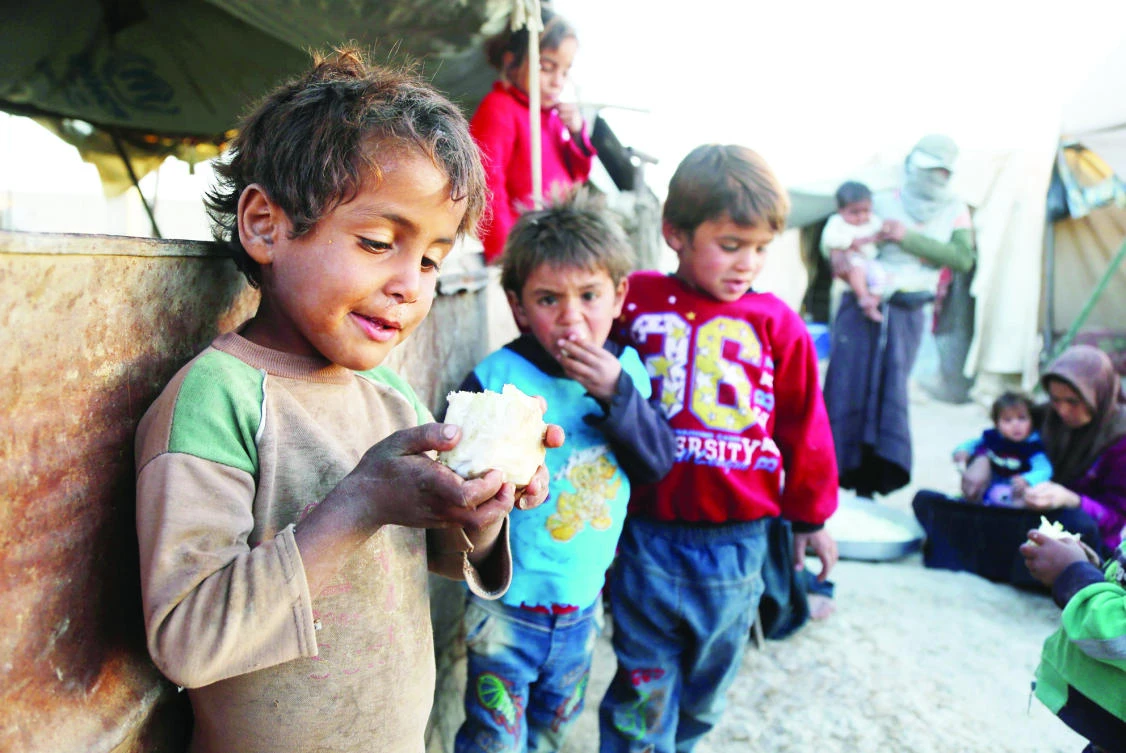 A Syrian child holds a piece of cauliflower in his hand at a refugee camp in Eastern Ghouta area outside the capital Damascus on Friday. (AFP)