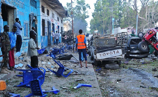 People stand among damages at the scene of a blast after two car bombs exploded in Mogadishu on Saturday, October 28, 2017. (AFP / Mohamed Abdiwahab)