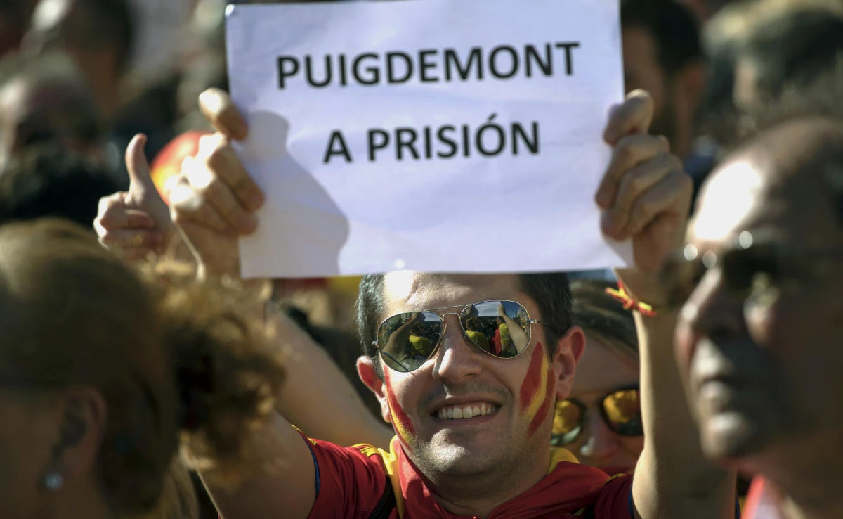 A man holds a banner reading in Spanish “Puigdemont go to prison” as nationalist activists protest during a mass rally against Catalonia’s declaration of independence, in Barcelona, Spain on Sunday, October 29, 2017. (File photo by AP)
