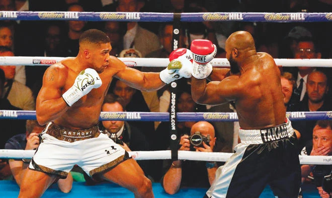 Anthony Joshua throws a punch at Carlos Takam during their bruising world heavyweight title fight in Cardiff on Saturday night. (AFP)