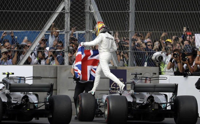 Mercedes driver Lewis Hamilton, of Britain, gets off his car holding a British flag as he celebrates at the end of the Formula One Mexico Grand Prix auto race at the Hermanos Rodriguez racetrack in Mexico City, on Sunday, Oct. 29, 2017. (AP Photo/Rebecca Blackwell)