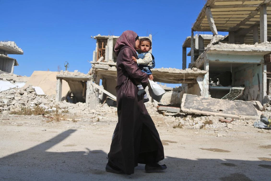 A Syrian woman heads to a medical center to have her child examined by doctors on Oct. 29, 2017, in Al-Nashabiyah in the besieged rebel-held Eastern Ghouta region outside Syria’s capital Damascus. (AFP/Amer Almohibany)