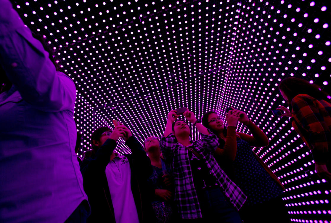 Visitors take pictures inside a tunnel lit by artists specializing in traditional Mexican lighting methods, in a work entitled "Dinamismo CDMX," at the International Festival of Lights in Mexico City, Friday, Nov. 17, 2017. This years festival, featuring installations and projections, is lighting up the capital's historic center until Nov. 19. (AP Photo/Rebecca Blackwell)