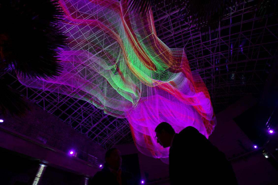 A security guard stands underneath "1.8" by American artist Janet Echelman, part of the International Festival of Lights in Mexico City, Friday, Nov. 17, 2017. This year's festival, featuring installations and projections, is lighting up the capital's historic center until Nov. 19.(AP Photo/Rebecca Blackwell)