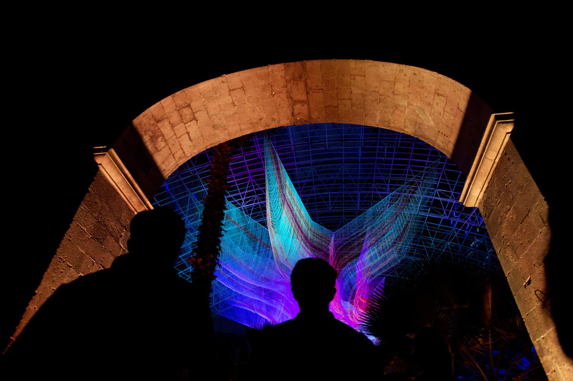 Visitors arrive to view "1.8" by American artist Janet Echelman, part of the International Festival of Lights in Mexico City, Friday, Nov. 17, 2017. This years festival, featuring installations and projections, is lighting up the capital's historic center until Nov. 19. (AP Photo/Rebecca Blackwell)