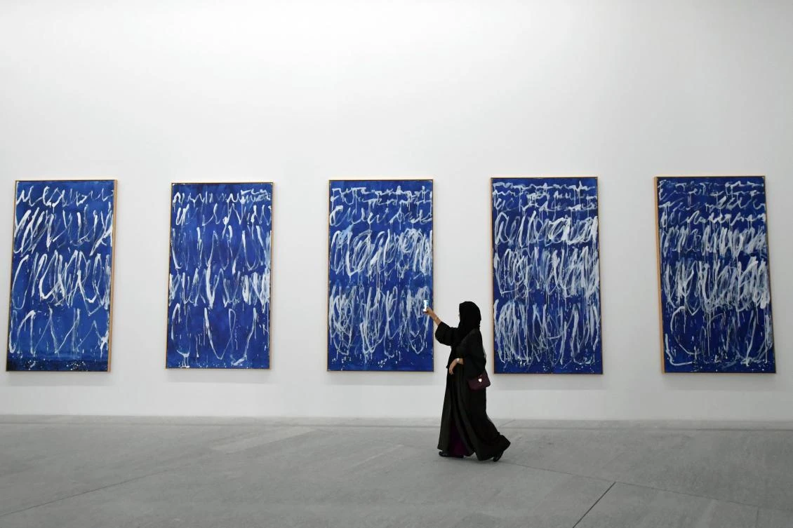 A visitor takes a photo of a piece of a series of nine panels titled "Untitled I-IX" by American artist Cy Twombly at the Louvre Abu Dhabi Museum on November 11, 2017 during its official opening to the public on Saadiyat island in the Emirati capital. More than a decade in the making, the Louvre Abu Dhabi opened its doors bringing the famed name to the Arab world for the first time. - RESTRICTED TO EDITORIAL USE - MANDATORY MENTION OF THE ARTIST UPON PUBLICATION - TO ILLUSTRATE THE EVENT AS SPECIFIED IN THE CAPTION / AFP / GIUSEPPE CACACE / RESTRICTED TO EDITORIAL USE - MANDATORY MENTION OF THE ARTIST UPON PUBLICATION - TO ILLUSTRATE THE EVENT AS SPECIFIED IN THE CAPTION