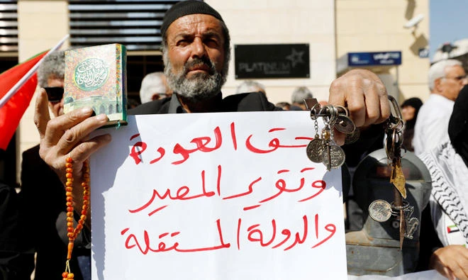 A Palestinian man holds a copy of the Qur’an, keys and a sign that reads: ‘Right of return, self determination and and the independent state’ during a protest calling on Britain to apologize for the Balfour Declaration, in the West Bank city of Ramallah on Oct. 18. (Reuters)
