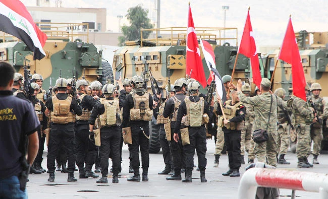 Turkish and Iraqi troops, some holding their national flags, participate in a ceremony at the Habur/Ibrahim Khalil border crossing with Iraq, near Silopi, southeastern Turkey, on Tuesday. (AP)