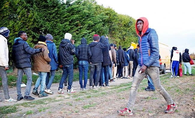 Sudanese migrants queue for food and garments, close the forest where they camp Ouistreham, on Monday. (REUTERS)