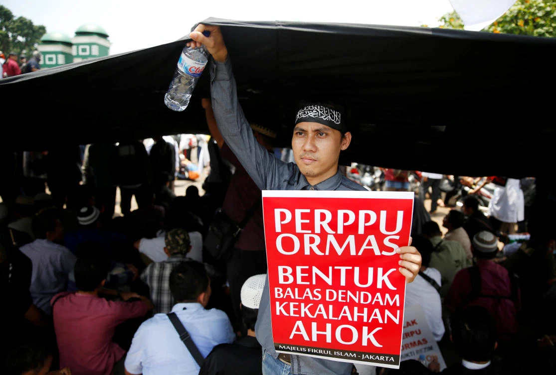 An Indonesian Islamist group member holds a placard during a protest against President Joko Widodo’s decree to disband certain groups, in front of the parliament building in Jakarta, Indonesia, Oct. 24, 2017. The placard reads: “Regulation for mass organizations is a form of revenge for the defeated Ahok.” (Reuters/Beawiharta)