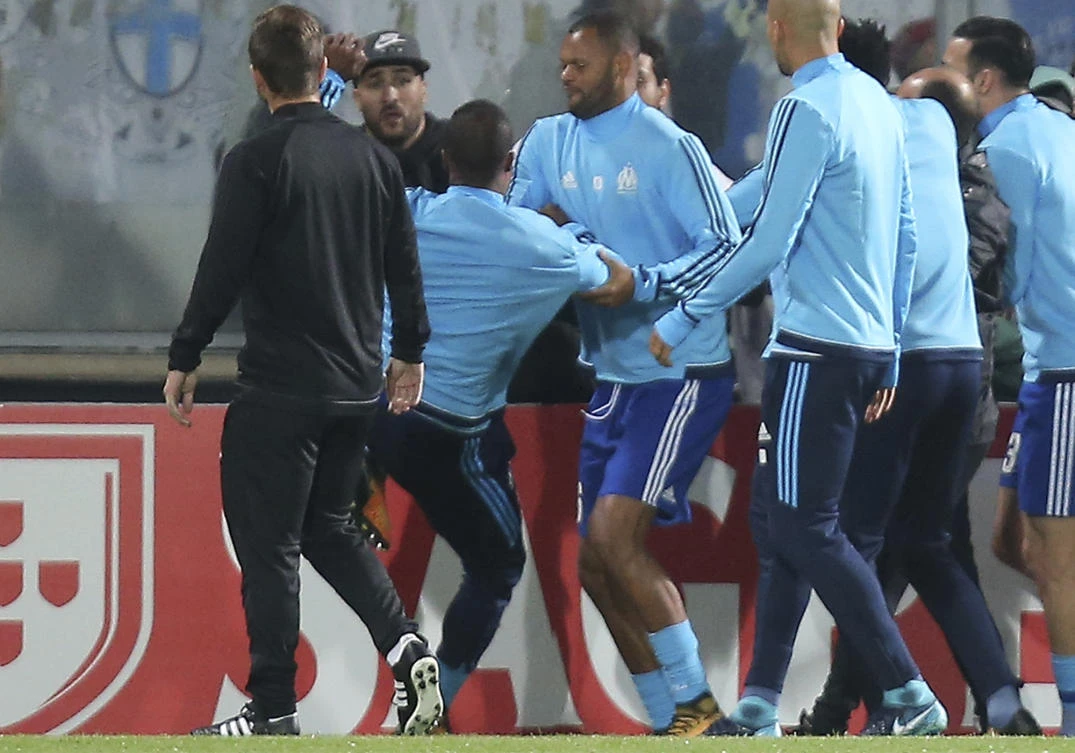 Marseille's Patrice Evra, third left, raises his foot trying to kick a man during a scuffle with Marseille supporters who trespassed into the field in Guimaraes, Portugal. (AP)