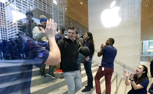 Chase Thilleman receives a high five from an Apple employee as he is first in line to buy the Apple iPhone X at the new Apple Michigan Avenue store along the Chicago River on Friday, Nov. 3, 2017, in Chicago. (AP Photo/Charles Rex Arbogast)