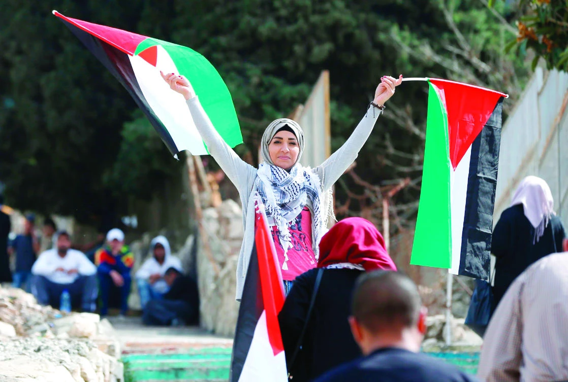 A Palestinian woman waves her national flag as she participates in a march on Thursday, in the center of the West Bank city of Ramallah, to protest the 100th anniversary of Britain’s Balfour Declaration. (AFP)