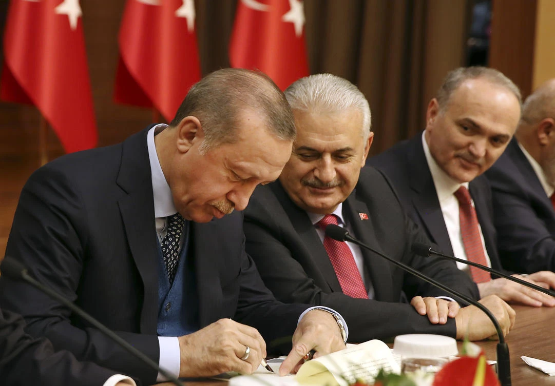 Turkey’s President Recep Tayyip Erdogan takes notes as Prime Minister Binali Yildirim looks on during an event in Ankara on Thursday. (AP)