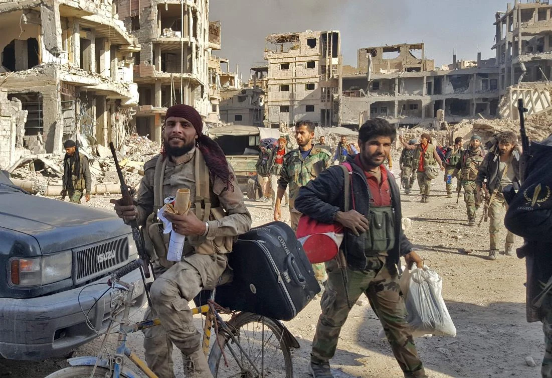 Syrian soldiers, and pro-government forces, are seen in front of damaged buildings in the eastern Syrian city of Deir Ezzor, which was the last city where Daesh still had a presence after being expelled from Hawija and Raqqa last month. (AFP)