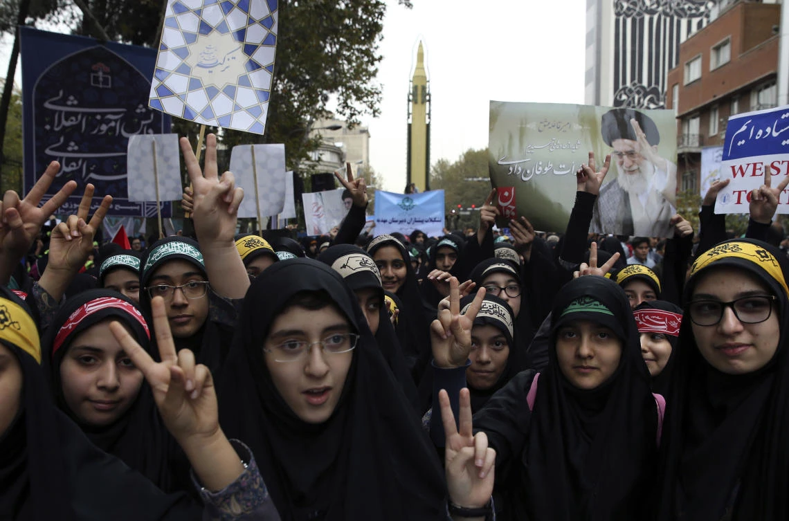 Iranian schoolgirls flash the victory sign in an annual gathering in front of the former US Embassy marking the anniversary of its 1979 takeover, while a surface-to-surface Sejjil missile is displayed by the Revolutionary Guard, at rear, in Tehran. (AP)