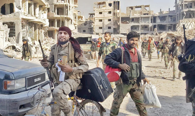 Syrian regime soldiers, and pro-government forces, are seen in front of damaged buildings in the eastern Syrian city of Deir Ezzor on Friday. (AFP)