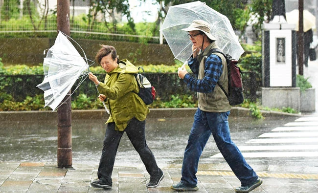 A woman have an umbrella turned inside out with strong wind in Tokyo, in this October 22, 2017 photo. (AFP)