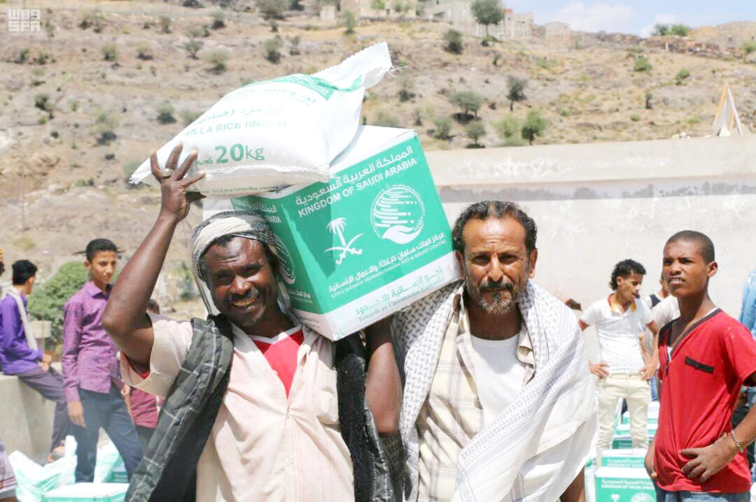 With smiles on their faces, Yemeni men carry the food packets received from KSRelief officials in Marib governorate, Yemen. (SPA)