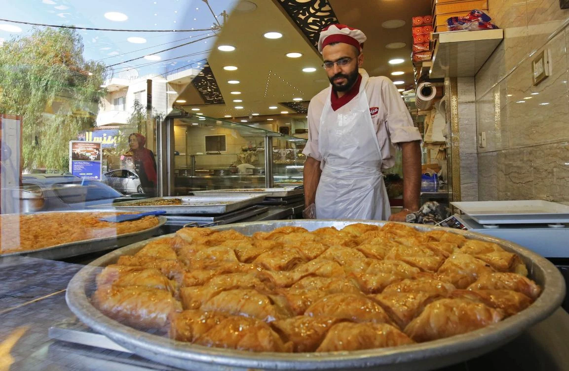 A man works at a shop selling traditional Syrian delicacies that is owned by Syrian refugee Mazen Obeido, who fled the conflict in his homeland, in the northern Jordanian town of Irbid on October 28, 2017. (AFP)