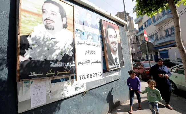 A picture taken on Sunday, Nov. 5, 2017, shows people walking past a banner bearing a portrait of Lebanese Prime Minister Saad Hariri in the capital Beirut a day following the announcement of his resignation. (AFP / ANWAR AMRO)