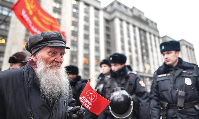 A Russian Communist supporter walks past police officers during a rally marking the 100th anniversary of the 1917 Bolshevik Revolution in downtown Moscow on Tuesday. (AFP)