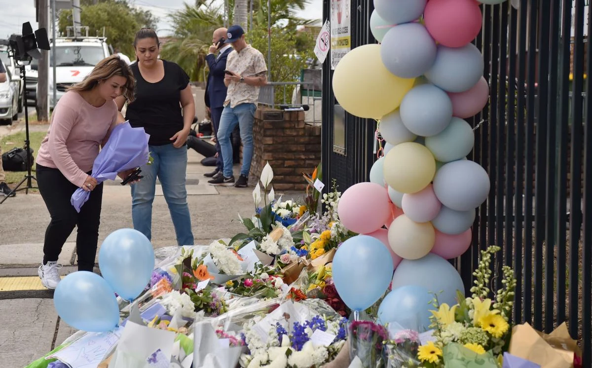 Women lay a floral tribute outside the Banksia Road Public School on Nov. 8, 2017, the day after a car crash killed two pupils inside the school’s premises in Sydney’s west. Distraught children and adults laid floral tributes at the school after two eight-year-old boys were killed by a car that smashed into their classroom, as the driver expressed her deep sorrow over the tragedy. (AFP/Peter Parks)
