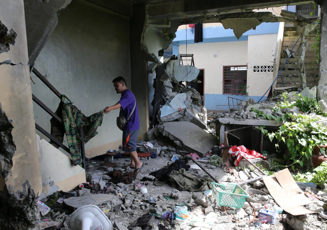A member of the local town security forces inspects personal belongings inside a damaged apartment house in a residential area in Malutlut district, Marawi city, southern Philippines October 27, 2017, which was believed to have been rented by pro-Daesh militant group leaders Isnilon Hapilon and Omar Maute before their battle in Marawi city. (REUTERS)