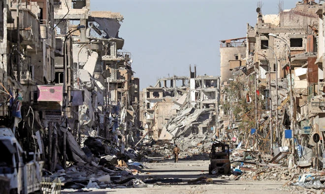 A fighter of Syrian Democratic Forces stands amid the ruins of buildings near the Clock Square in Raqqa.(Reuters)