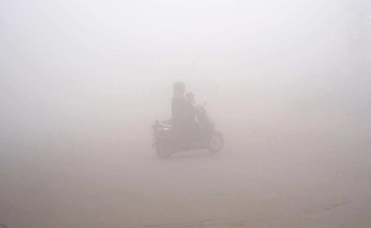 A woman drives a scooter through the morning fog to drop off a child to school in Greater Noida, near New Delhi, India, on Thursday, November 9, 2017. (AP)