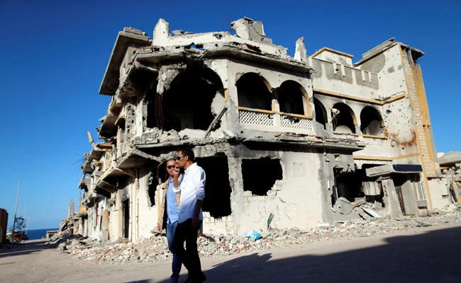 Men walk past the ruins of a building that was destroyed during clashes between Libyan forces and Daesh in Sirte, Libya. (Reuters)