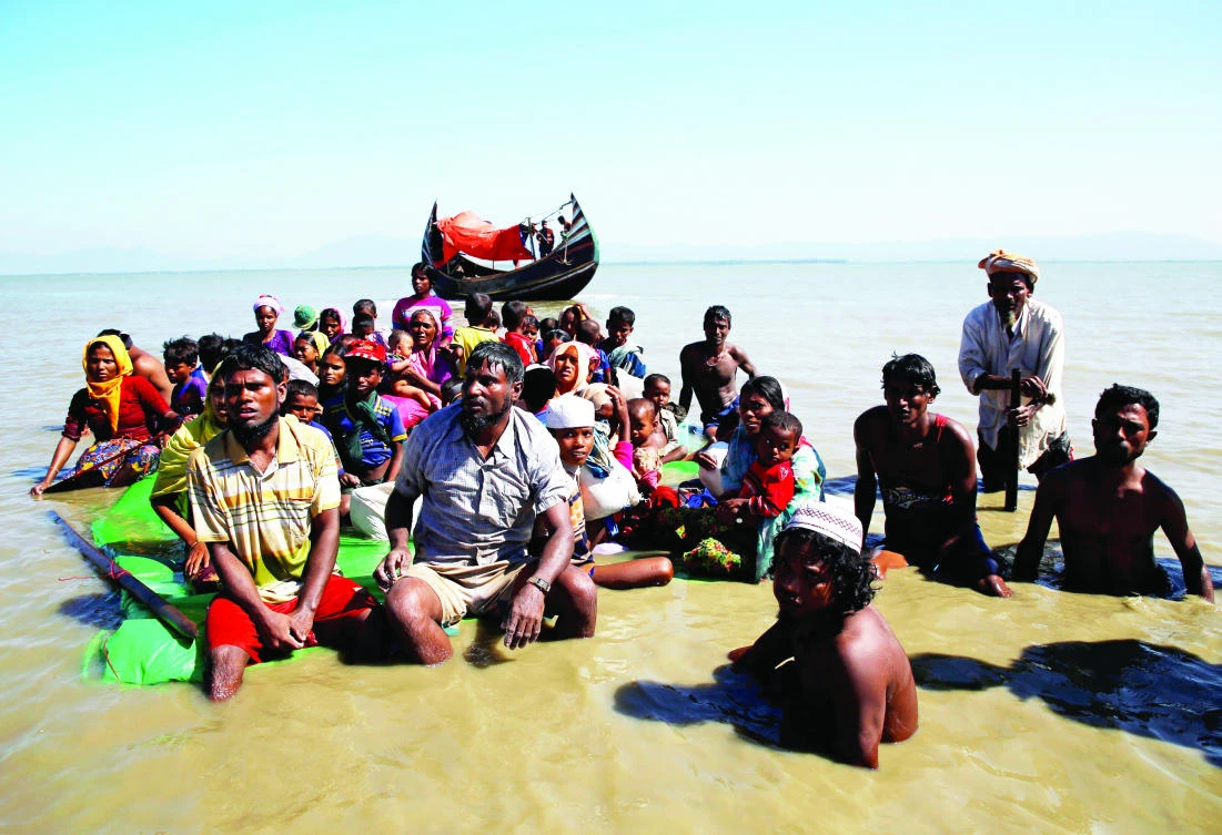 Rohingya refugees sit on a makeshift boat as they get interrogated by the Border Guard of Bangladesh after crossing the Bangladesh-Myanmar border, at Shah Porir Dwip near Cox's Bazar Friday. (Reuters)