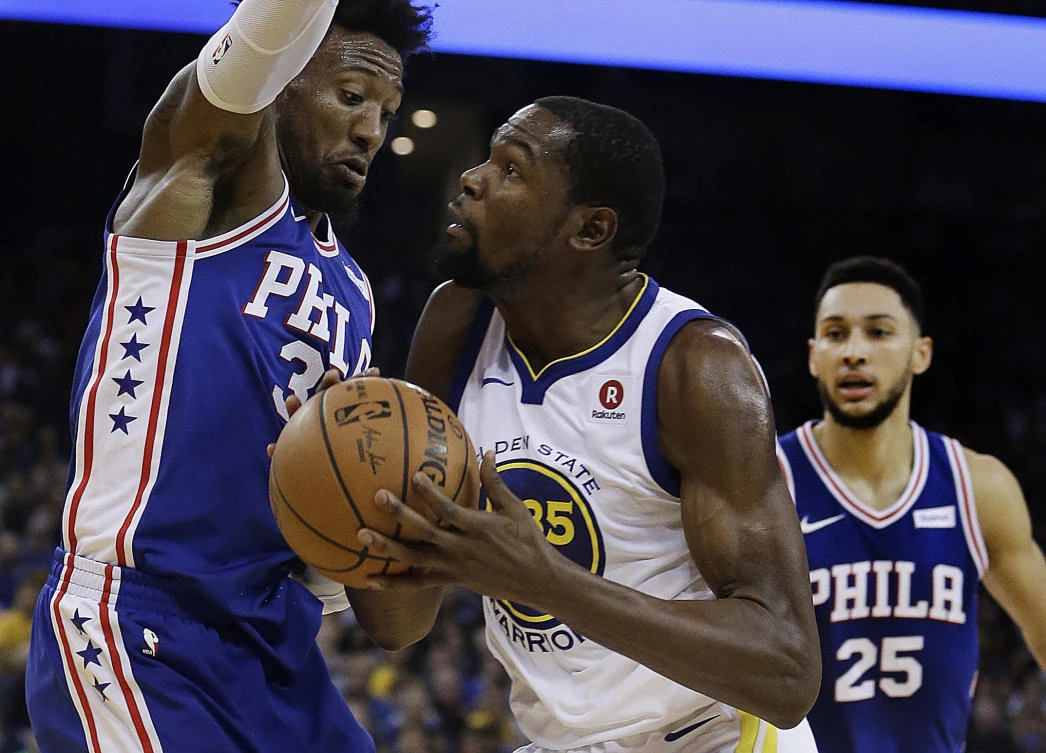 Golden State Warriors’ Kevin Durant drives the ball against Philadelphia 76ers’ Robert Covington, left, and Ben Simmons during their NBA basketball game on Saturday in Oakland. (AP)