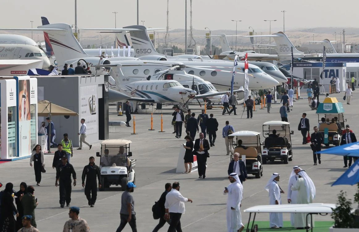 Participants walk past aircraft on stationary display at opening day of Dubai Airshow on November 12. (AFP)