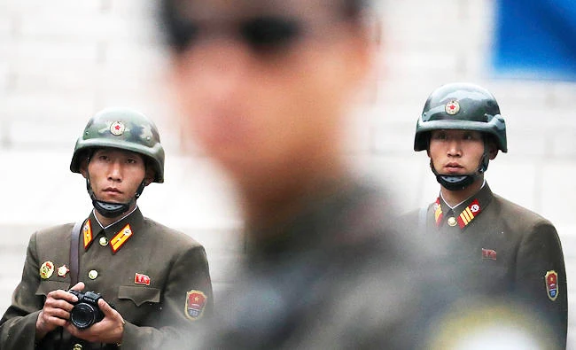 In this April 17, 2017, photo, two North Korean soldiers look at the south side as a South Korean soldier, center, stand guard at the border village of Panmunjom which has separated the two Koreas since the Korean War, South Korea. (AP)