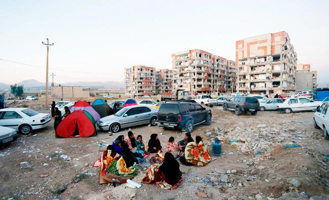 Residents huddle by a fire in an open area following a 7.3-magnitude earthquake at Sarpol-e Zahab in Iran's Kermanshah province on Monday. (AFP)