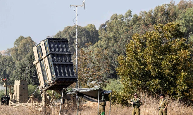 Israeli soldiers stand guard next to an Iron Dome defense system, designed to intercept and destroy incoming short-range rockets and artillery shells, deployed in central Israel, on Tuesday, November 14, 2017. (AFP)