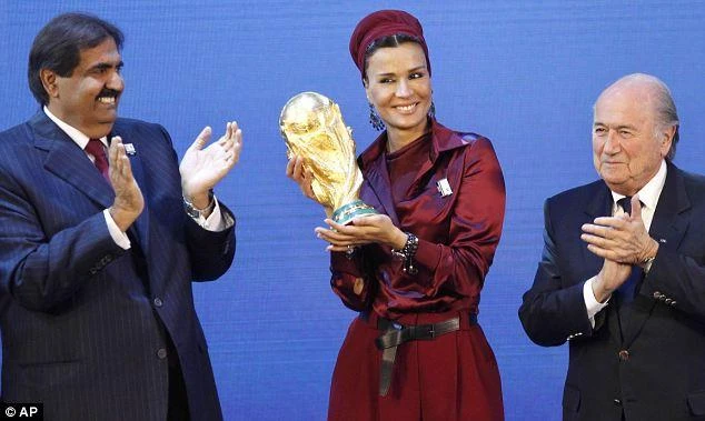 Qatar’s Sheika Mozah bint Nasser Al-Misned holds the World Cup trophy as the emir Sheikh Hamad bin Khalifa Al-Thani (left) applauds following the controversial announcement in 2010. (AP)