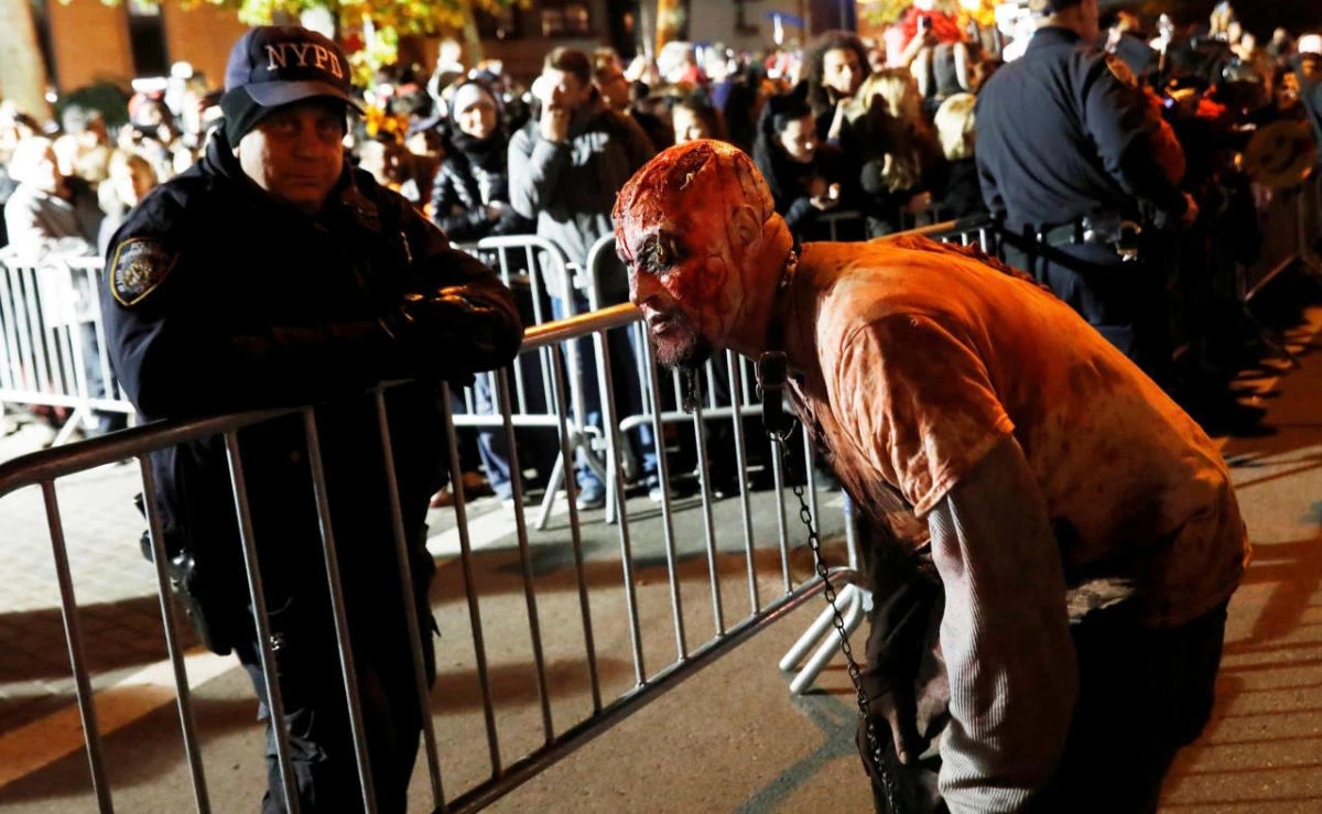 A person in costume waits at a barricade with police officers for the New York City Halloween parade in New York City, NY, US on October 31, 2017. (File photo by Reuters)