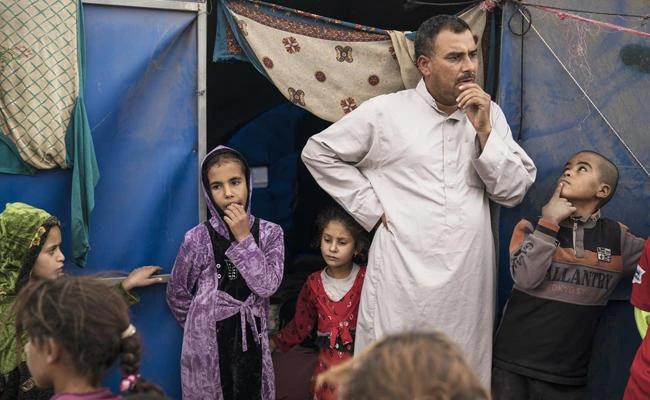 A family stands outside its tent in the Hamam Alil camp for displaced people, south of Mosul, Iraq. (AP)