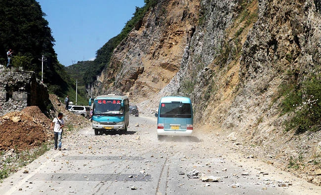 Two buses make their way across a road full of fallen rocks after a series of earthquakes hit the area at the border of southwest China's Yunnan and Guizhou province on Friday. (AFP)