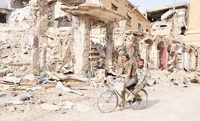 Men ride a bicycle in the eastern Syrian city of Deir Ezzor during a military operation by government forces against Daesh group, in this photo taken on November 4, 2017. (AFP)